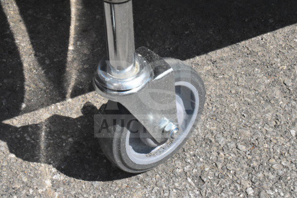 Close-up of a robust commercial caster wheel attached to a metal leg, suitable for heavy-duty use on tiered carts.
