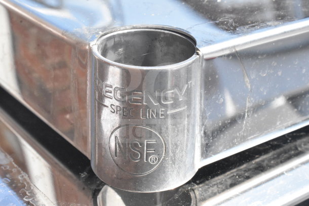 Regency 3 Tier Cart corner detail showing NSF mark, indicating commercial use. Polished metal surface, slight wear visible.