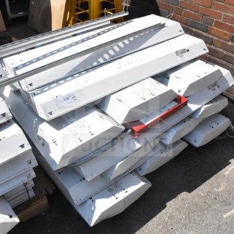 Howard HFA3E654APSMV light fixtures, stack of 18, 120-277 volts, used condition. Visible labels and industrial setting.