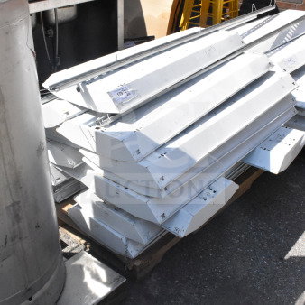 Stack of 12 Howard HFA3E654APSMV light fixtures, 120-277 volts. Good condition, metal housing, auction lot number visible.