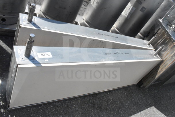 Two industrial metal units with cylindrical attachments, labeled "TX 184", in good condition, offered at auction.