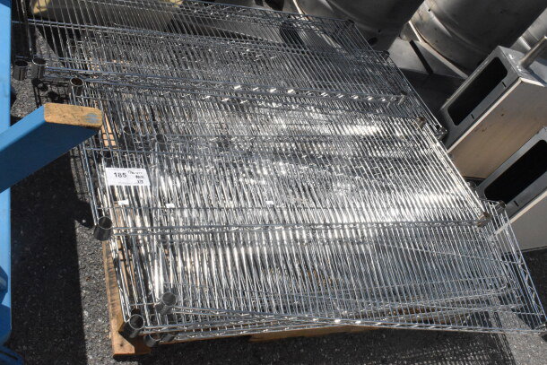 Lot of 18 chrome finish wire shelves, shiny condition, stacked on a pallet. Label indicates item number "185."
