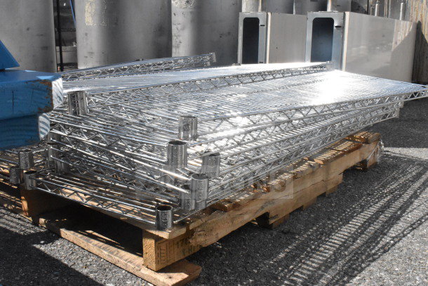 Lot of 18 chrome finish wire shelves stacked on a pallet, in good condition, ideal for storage solutions.