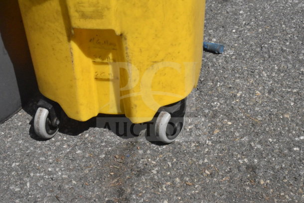 Yellow mop bucket with caster wheels on pavement. Markings indicate measurements. Visible wear from usage.