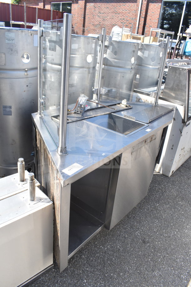 Stainless steel counter with bay and sneeze guard, featuring a sink and storage area, in used condition.