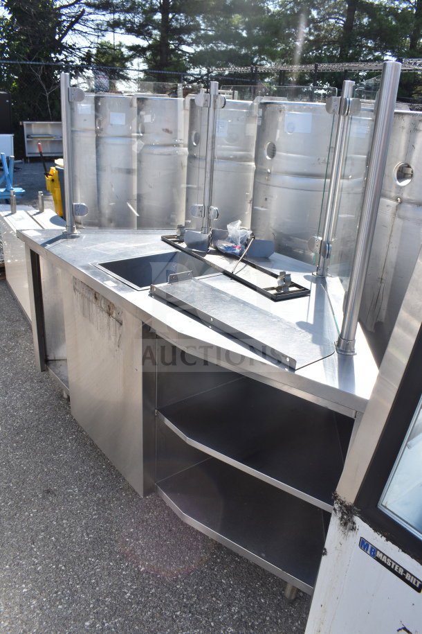 Stainless steel counter with bay, sneeze guard, and shelves, ideal for commercial use, in good condition.