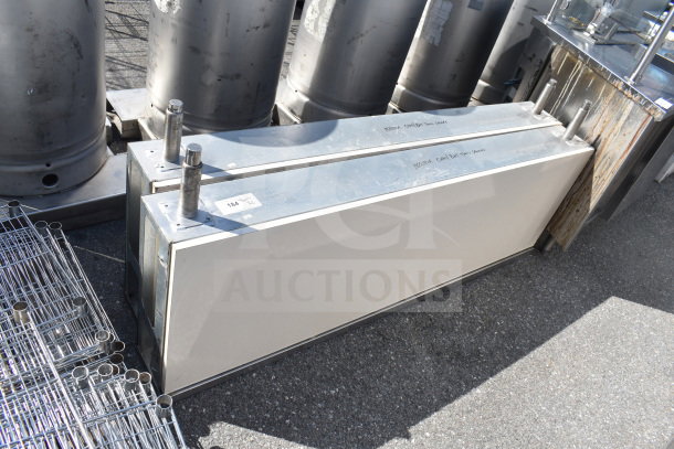 Two stainless steel industrial units on auction, featuring cylindrical components, metal housing, with visible condition labels.