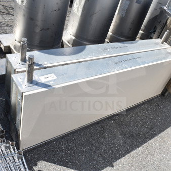 Two stainless steel industrial units on auction, featuring cylindrical components, metal housing, with visible condition labels.