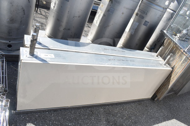 Metal industrial units with silver tops and two vertical pipes each. Markings indicate model details. Good condition.