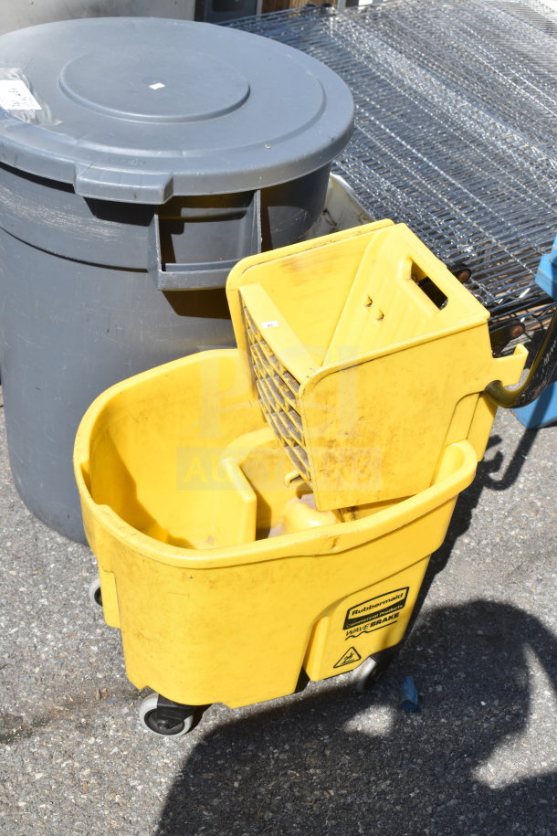Gray trash can and yellow Rubbermaid mop bucket, both used, on outdoor surface.