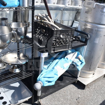 Black poly 2-tier cart with contents, including hoses and an umbrella, on commercial casters. Auction tag visible.