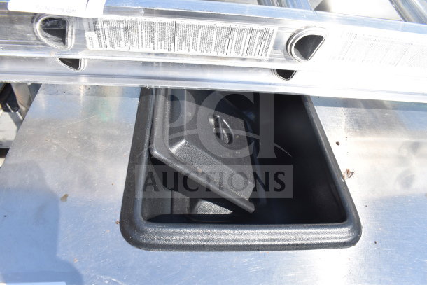 Steel commercial counter with four doors, visible storage bin on top, slight wear, auction tag partially visible.