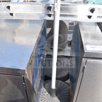 Two round, black umbrella bases in used condition, designed for stability. Tags indicate lot and quantity numbers.