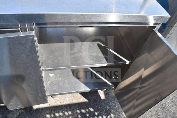 Commercial counter with 2 bay sink, 4 doors, stainless steel, shelves visible, in used condition.
