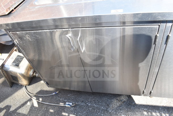 Commercial stainless steel counter, featuring a 2-bay sink and 4 doors. Includes plumbing connections. Slight surface wear.