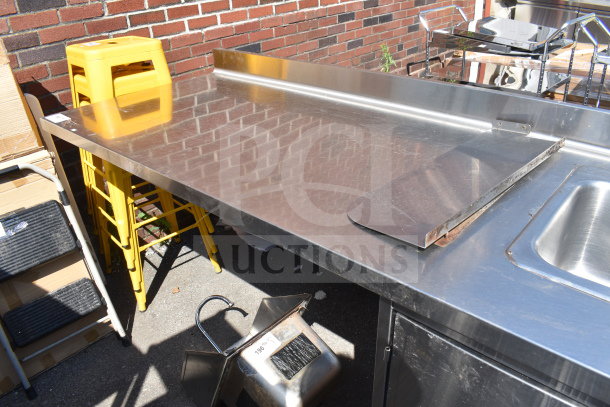 Stainless steel commercial counter with 2 bay sink, 4 doors, and backsplash, showing minimal wear. Includes yellow stools.