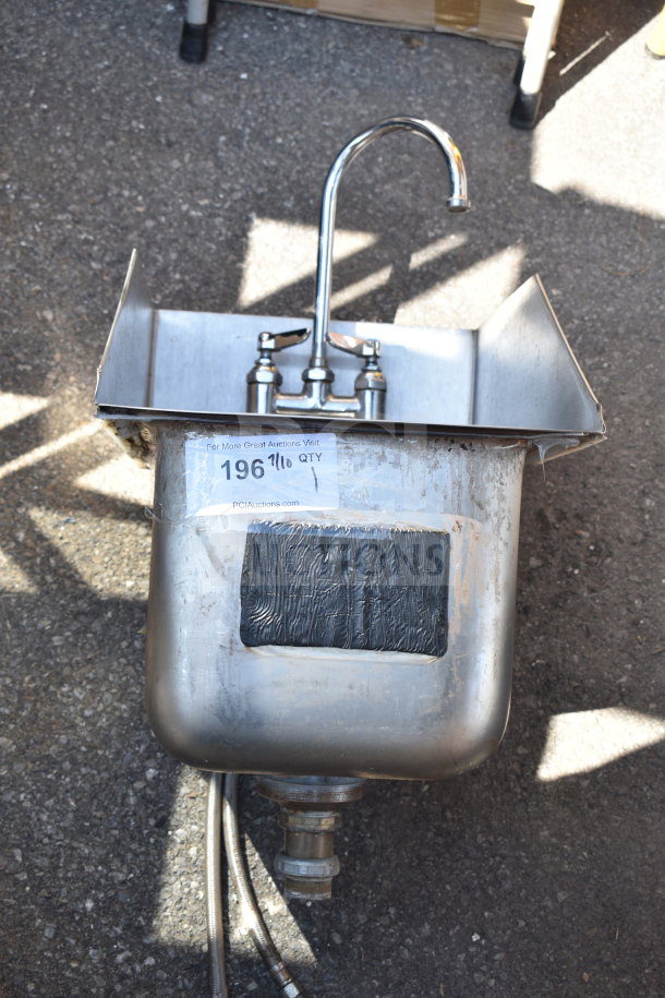 Single bay wall mount sink with faucet, stainless steel, attached hoses, some surface wear, label with auction details visible.