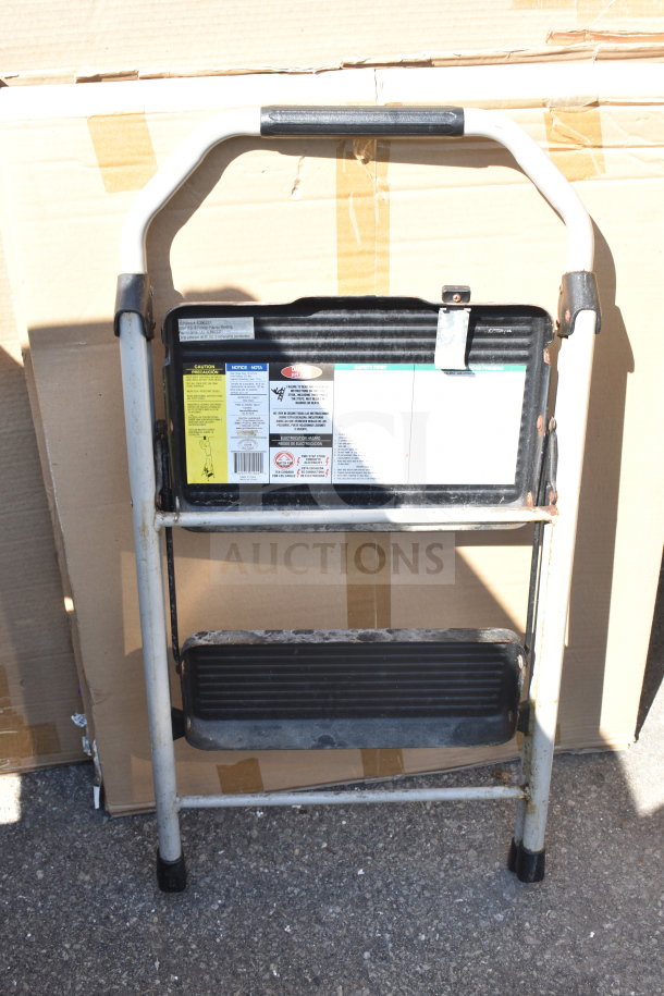 Metal A-frame ladder with two steps and visible safety labels; slight wear on the steps, sturdy condition.