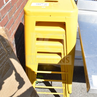 Four yellow Tolix style stools stacked, in good condition, with a visible auction label on the top stool.