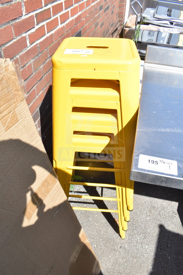 Four stackable yellow Tolix style stools, in good condition, with a glossy finish. Auction tag visible on top stool.