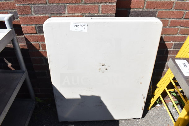 White bi-fold folding table, showing light stains and minor wear. Auction tag "200 7/10 QTY 1" visible.