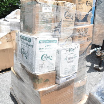 Pallet of scratch and dent boxes containing brand new cold cups, napkins, and hot cups, wrapped in plastic.