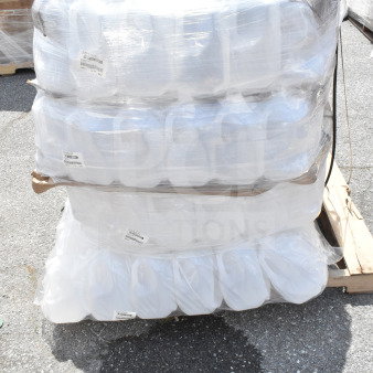 Bulk pallet of new plastic gallon containers wrapped in plastic. Labeled as scratch and dent, stacked in four tiers.