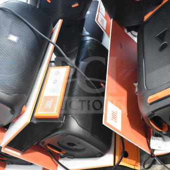 3 JBL speakers on display, featuring sleek black design with orange accents. Includes power controls. Brand labels visible.