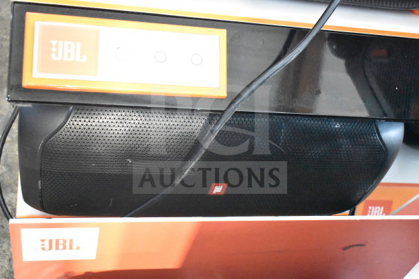 JBL speaker on display shelf. Visible JBL logos. Black grille and orange branding. Used condition, ideal for retail.