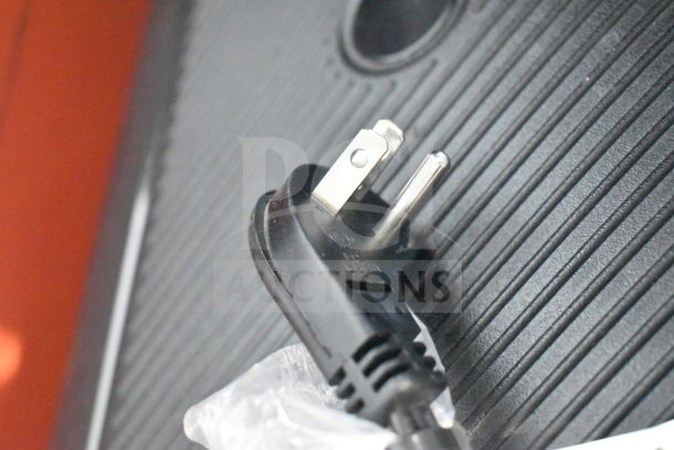Black power plug on a textured surface, possibly related to a JBL speaker in a store display.