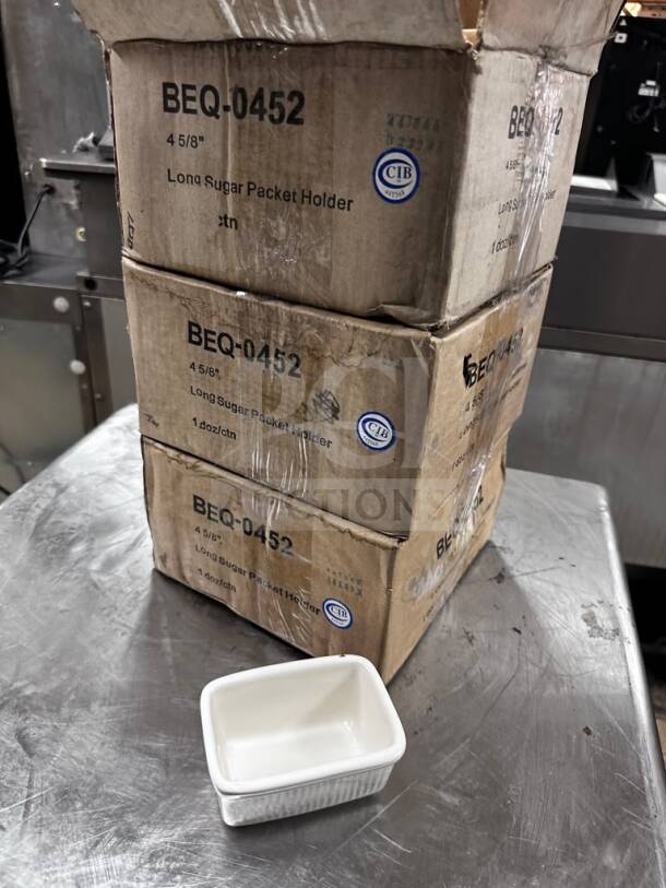 Tuxton BEQ-0452 eggshell china sugar packet holder, new, commercial-ready. Boxes labeled with model and size details.