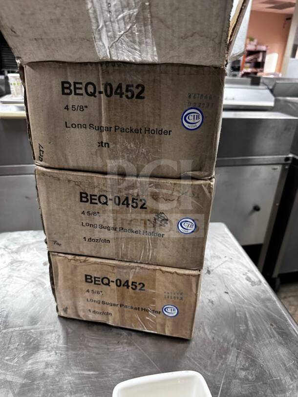 Tuxton BEQ-0452 sugar packet holders in cartons, eggshell china, new condition, quantity 36, ready for commercial use.