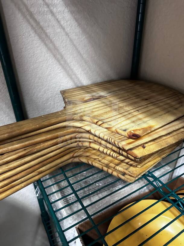 Stack of nine well-maintained wooden pizza peels on a metal shelf, ready for commercial use.