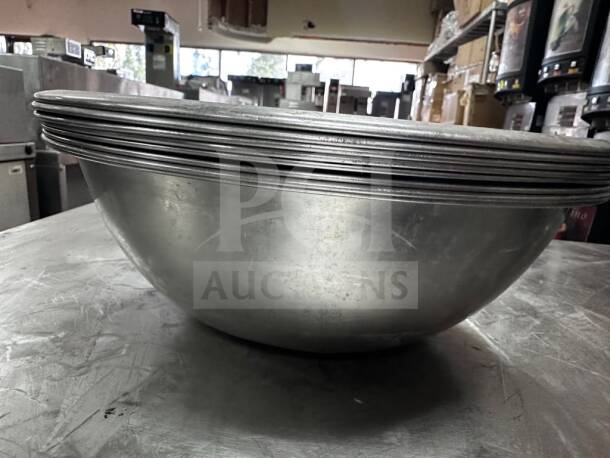 Stack of seven 10" stainless steel commercial salad/mixing bowls, well-maintained, for commercial use.
