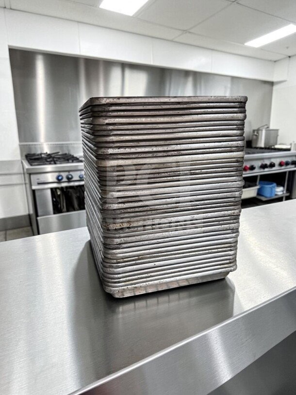 Stack of 40 Commercial Kitchen Smallwares 1/4 Size Aluminum Sheet Pans, 18 Gauge, ready for commercial use, on stainless steel counter.
