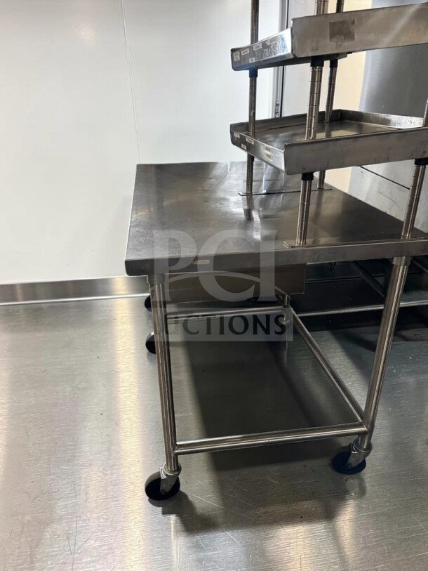 Pristine commercial stainless steel work table, 60" x 34", with over shelf, under table racks, and casters. Model GEN-S-TBL-1189.