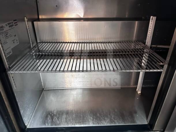 True TSSU-60-24M-B-ST-HC refrigerated prep table interior with shelving, label showing model and specifications. Superior condition.