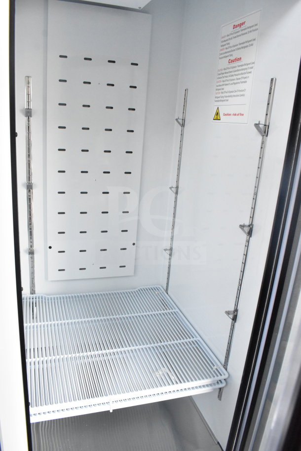 "Interior of Migali C-49RM-HC commercial cooler showing adjustable shelves, vented back panel, and caution label."
