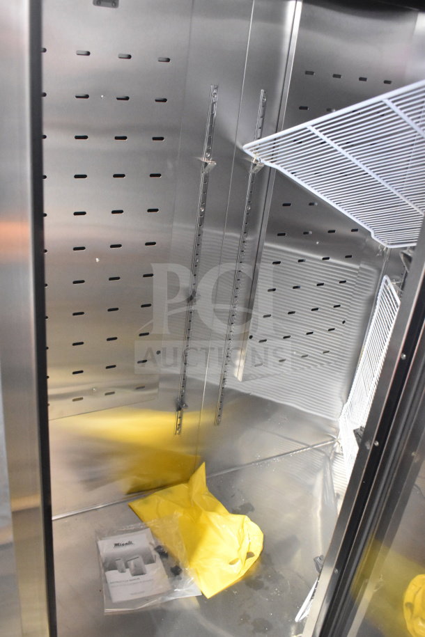 Brand new 2017 Migali C-3R-HC commercial 3-door cooler interior, with metal shelves, and instruction manual visible.