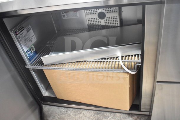 Brand new 2026 True TSSU-60-16D-2-HC commercial sandwich prep table interior. Features cooling unit, shelves, and cardboard box.