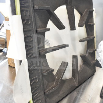 "American Range cast iron burner part, new condition, with visible brand name embossing, positioned on a metallic surface."