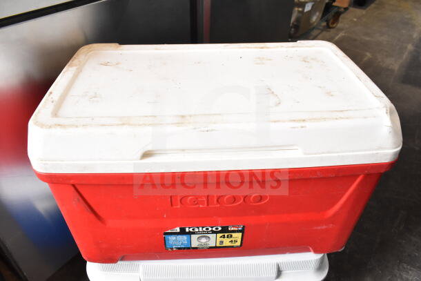 Red Igloo cooler with white lid, visible label showing "48 Qt" capacity, some wear indicated on surface.