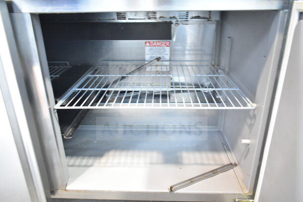 2019 Delfield 4460NP-24M commercial prep table interior, stainless steel, with wire shelves and a "Danger" label.