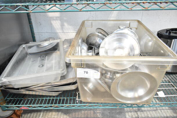 Lot of various stainless steel items including footed plates and chafer lids in plastic bin on metal shelf, quantity tag visible.