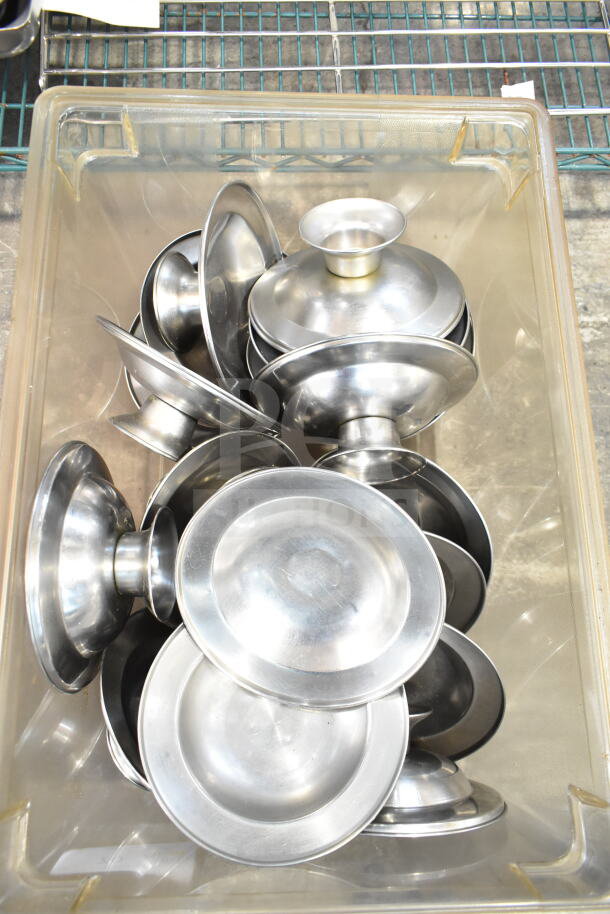 Lot of metal footed plates and chafer lids; silver tone; stored in a plastic bin; used condition.