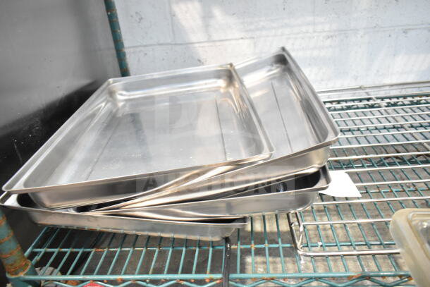 Stacked stainless steel trays on a metal rack, in good condition, part of a lot including footed plates and chafer lids.