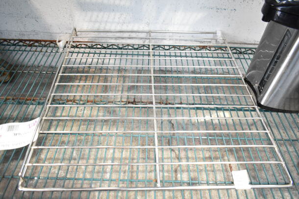 Metal rack shelf, used condition, with visible item tags placed on a wire storage shelf.
