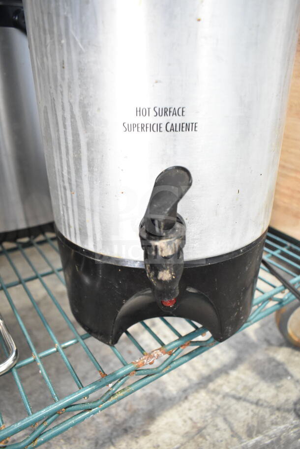 Hamilton Beach beverage dispenser with faucet, metal exterior marked with "Hot Surface," in used condition on metal shelf.