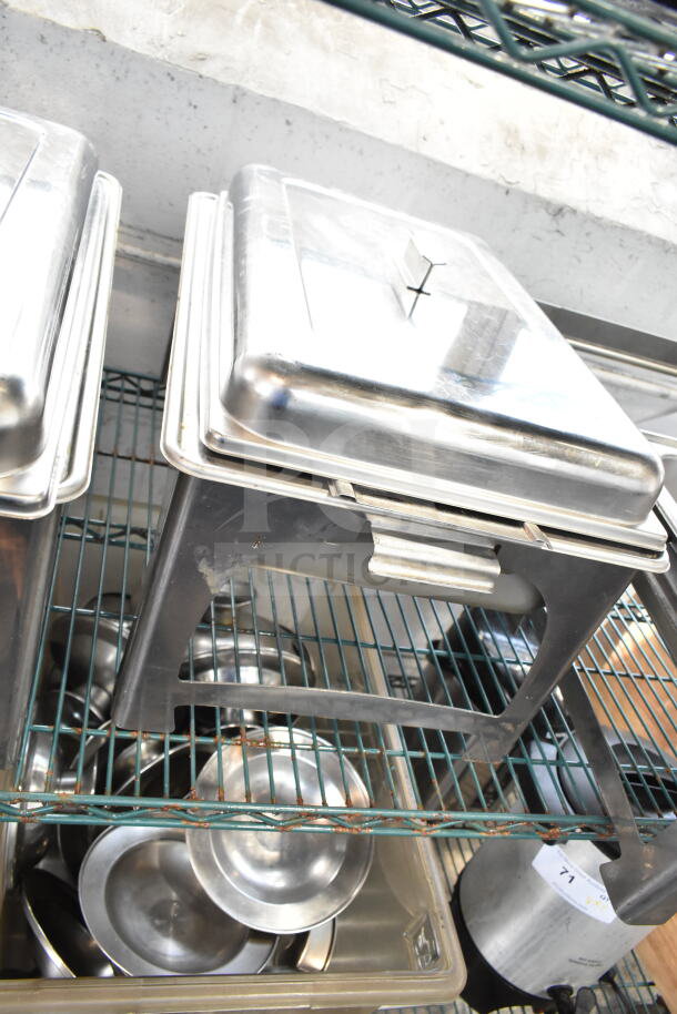 Four stainless steel chafing dishes are stacked on a wire rack. They are in good condition, suitable for catering.