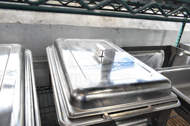 Set of 4 stainless steel chafing dishes with lids. Used condition, stackable design, ideal for catering or buffets.